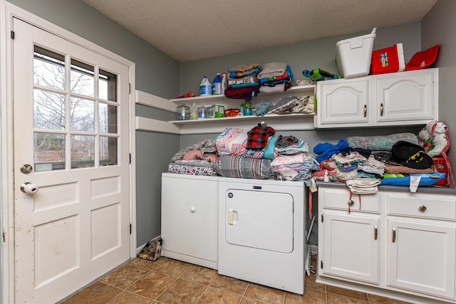 clothes washing area with cabinet space, separate washer and dryer, a textured ceiling, and light tile patterned flooring