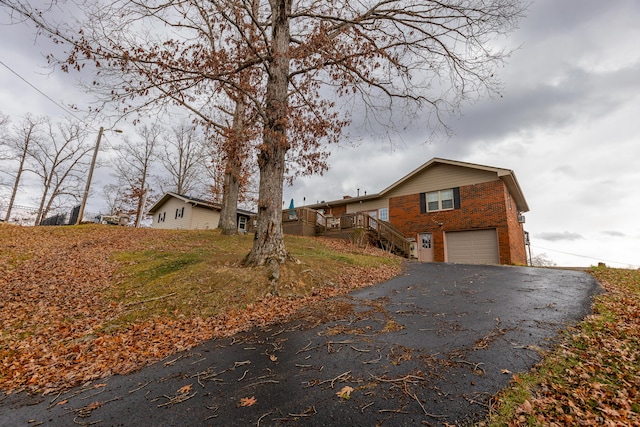 exterior space featuring an attached garage, aphalt driveway, and brick siding