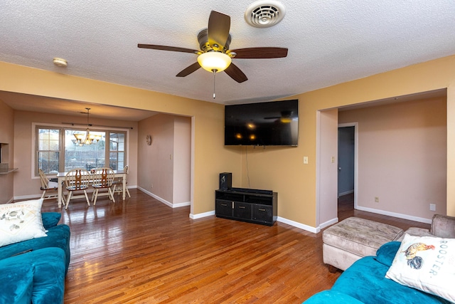 living room with visible vents, a textured ceiling, baseboards, and wood finished floors