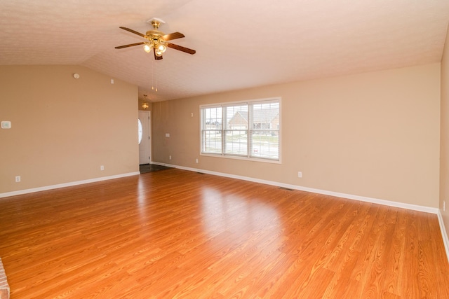 empty room with a ceiling fan, lofted ceiling, baseboards, and light wood finished floors