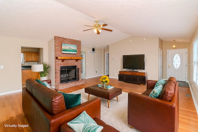 living area with baseboards, lofted ceiling, ceiling fan, light wood-type flooring, and a fireplace