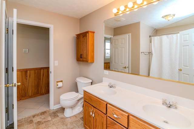 bathroom featuring a sink, toilet, and double vanity