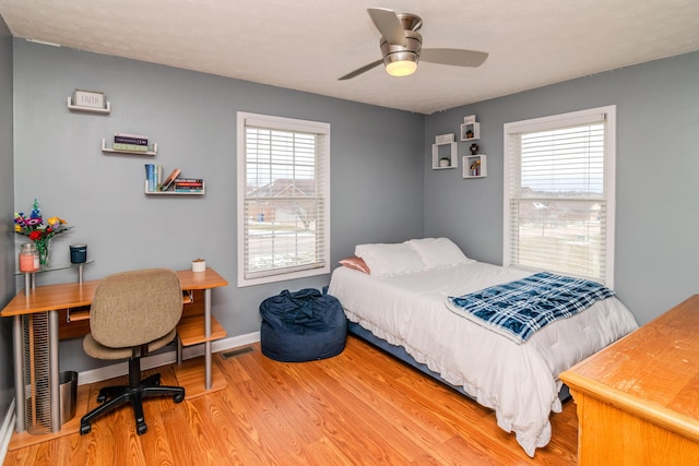 bedroom featuring multiple windows, wood finished floors, visible vents, and baseboards