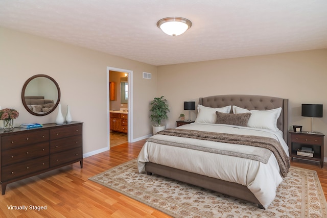 bedroom with baseboards, visible vents, light wood finished floors, and ensuite bathroom