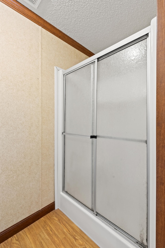 bathroom featuring a shower with door, hardwood / wood-style floors, and a textured ceiling