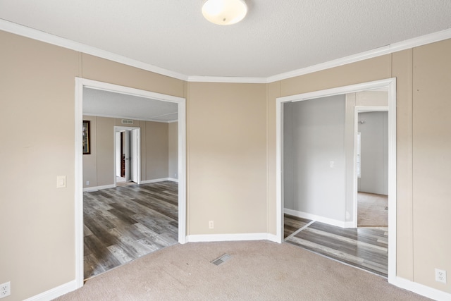 empty room with dark colored carpet, ornamental molding, and a textured ceiling