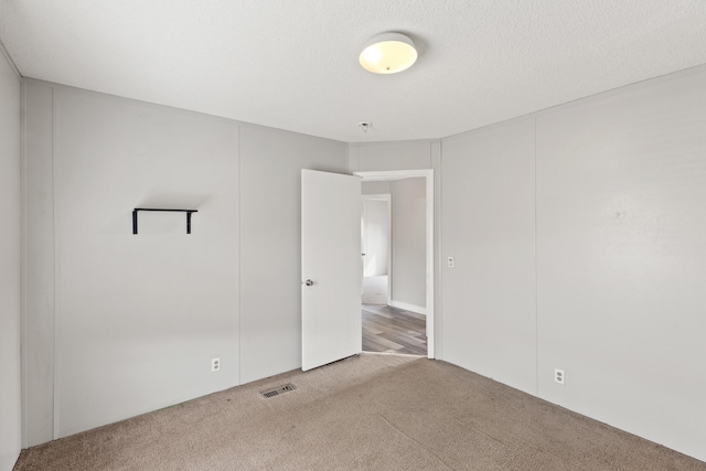 empty room featuring a textured ceiling and carpet flooring