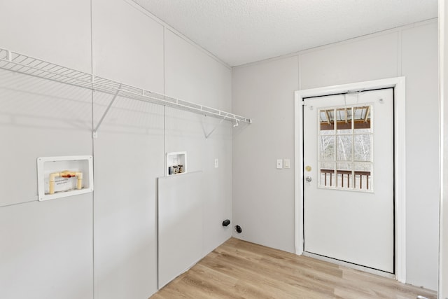 clothes washing area featuring hookup for a washing machine, light hardwood / wood-style floors, and a textured ceiling