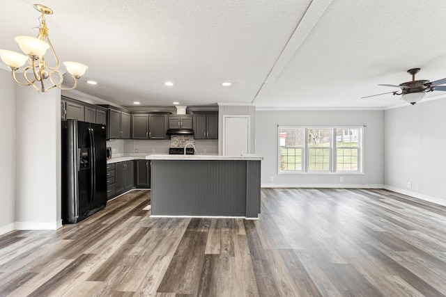 kitchen featuring pendant lighting, ornamental molding, a center island with sink, dark hardwood / wood-style flooring, and black refrigerator with ice dispenser