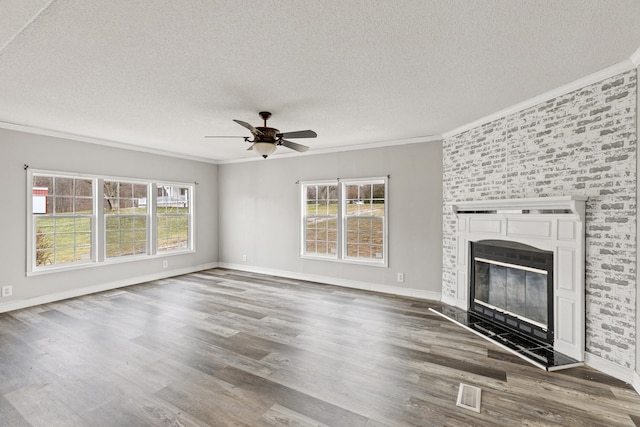 unfurnished living room featuring a large fireplace, ceiling fan, crown molding, dark wood-type flooring, and a textured ceiling