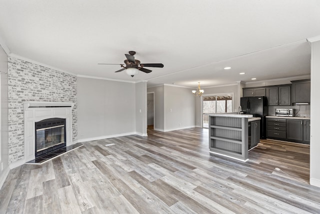 kitchen featuring light hardwood / wood-style flooring, gray cabinetry, a large fireplace, a kitchen island, and black refrigerator with ice dispenser