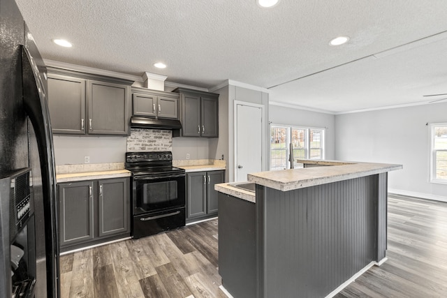 kitchen featuring gray cabinetry, ornamental molding, a kitchen island with sink, and black appliances