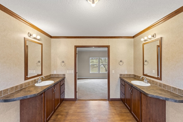 bathroom with vanity, hardwood / wood-style floors, ornamental molding, and a textured ceiling