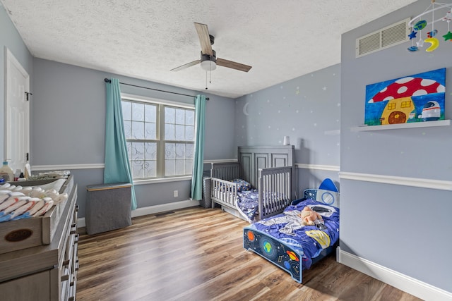 bedroom featuring ceiling fan, wood-type flooring, and a textured ceiling