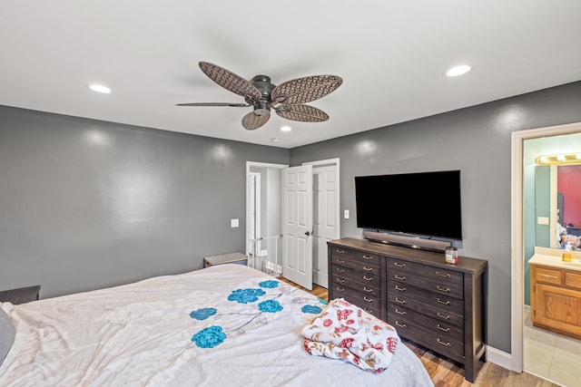 bedroom with ceiling fan, ensuite bath, and light hardwood / wood-style flooring