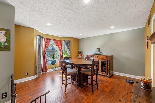 dining space featuring dark wood-type flooring and a textured ceiling