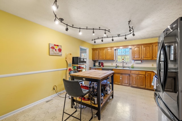 kitchen with black refrigerator, sink, a textured ceiling, and dishwasher