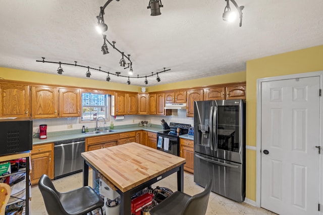 kitchen featuring sink, backsplash, a center island, stainless steel appliances, and a textured ceiling