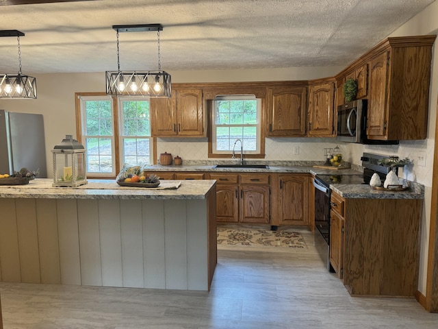 kitchen with sink, tasteful backsplash, decorative light fixtures, appliances with stainless steel finishes, and dark stone counters