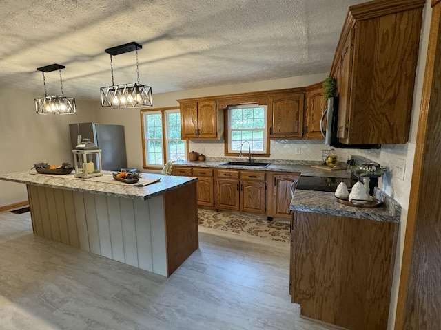 kitchen featuring appliances with stainless steel finishes, decorative light fixtures, sink, backsplash, and a center island