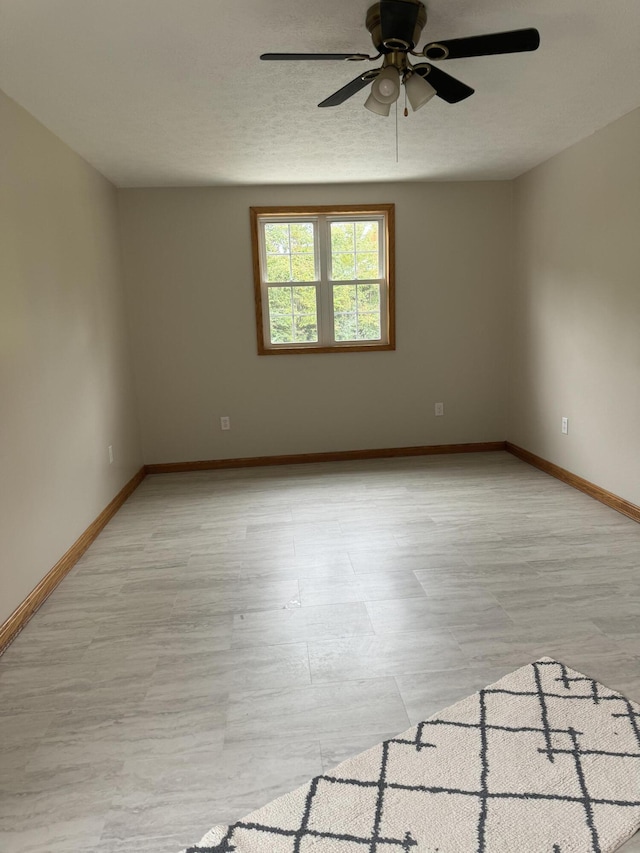 empty room with ceiling fan and a textured ceiling