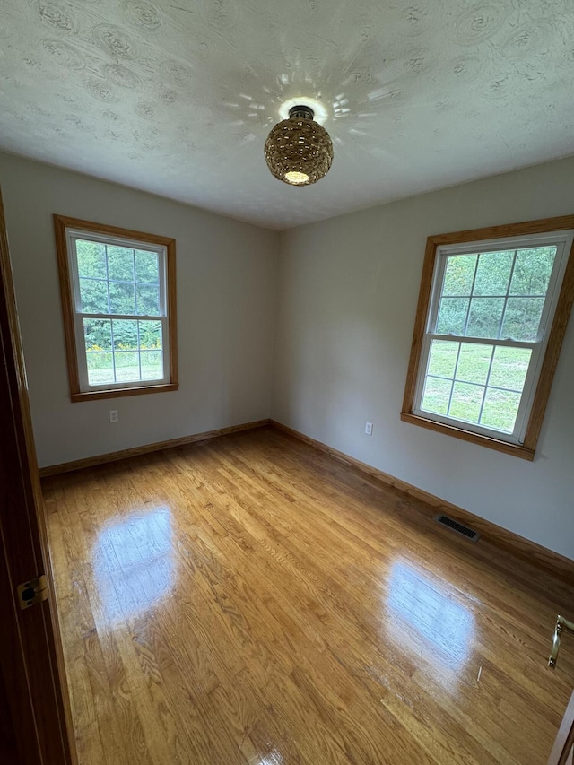 unfurnished room with light hardwood / wood-style floors and a textured ceiling