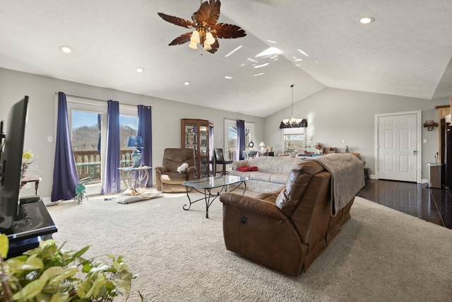 carpeted living room featuring lofted ceiling, plenty of natural light, and ceiling fan with notable chandelier