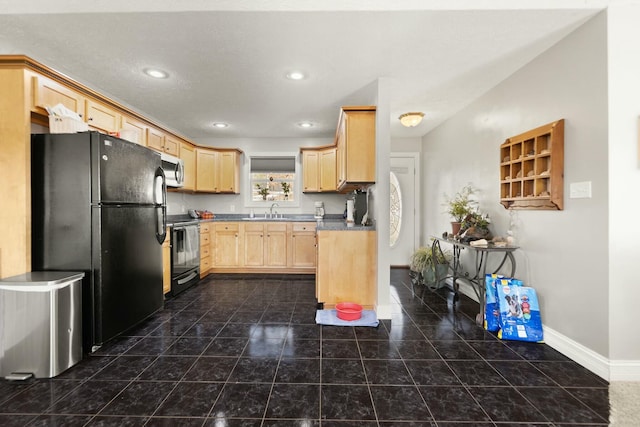 kitchen featuring black refrigerator, range with electric stovetop, dark tile patterned floors, and light brown cabinets