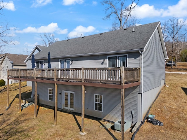 rear view of house featuring central AC unit, a deck, and a lawn