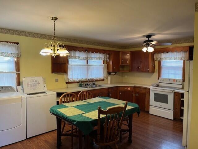 kitchen featuring pendant lighting, sink, white electric range, dark wood-type flooring, and washing machine and clothes dryer