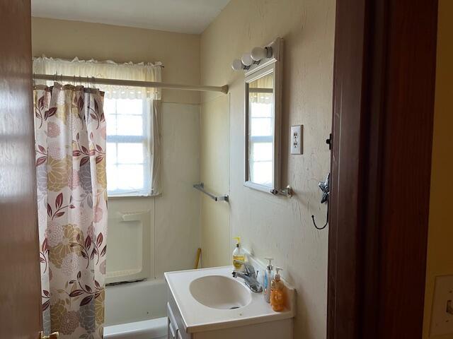 bathroom with vanity, a healthy amount of sunlight, and shower / bath combination with curtain