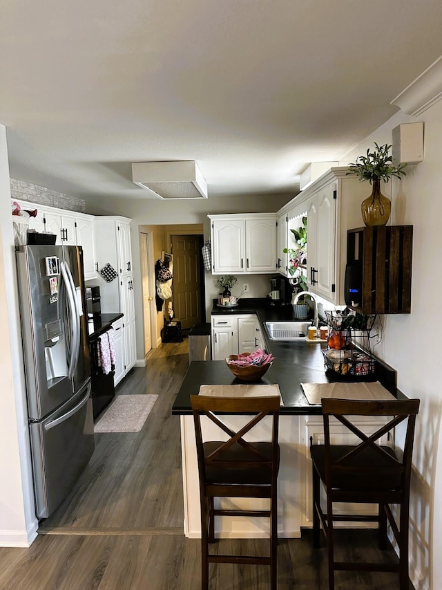 kitchen featuring dark hardwood / wood-style floors, stainless steel fridge with ice dispenser, sink, white cabinets, and kitchen peninsula