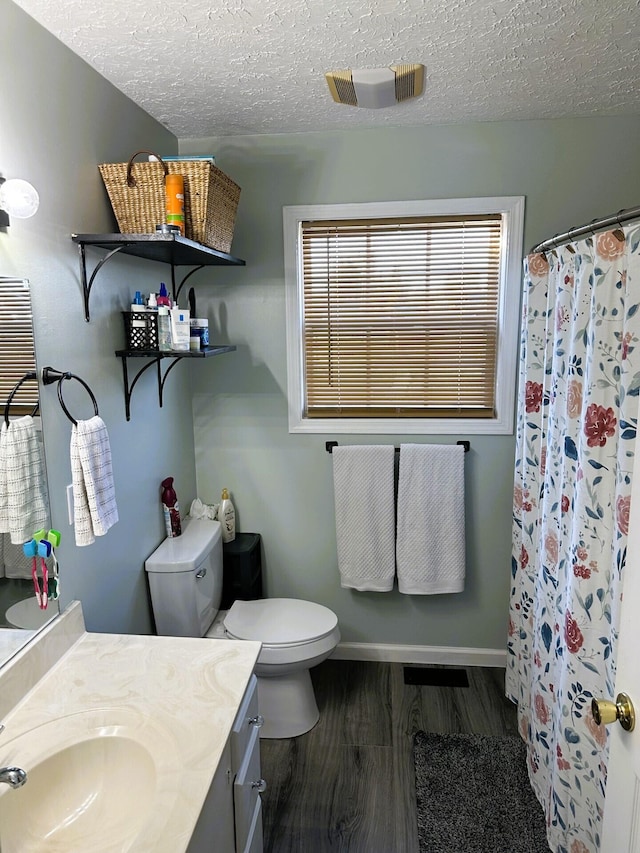 bathroom featuring walk in shower, toilet, wood-type flooring, a textured ceiling, and vanity