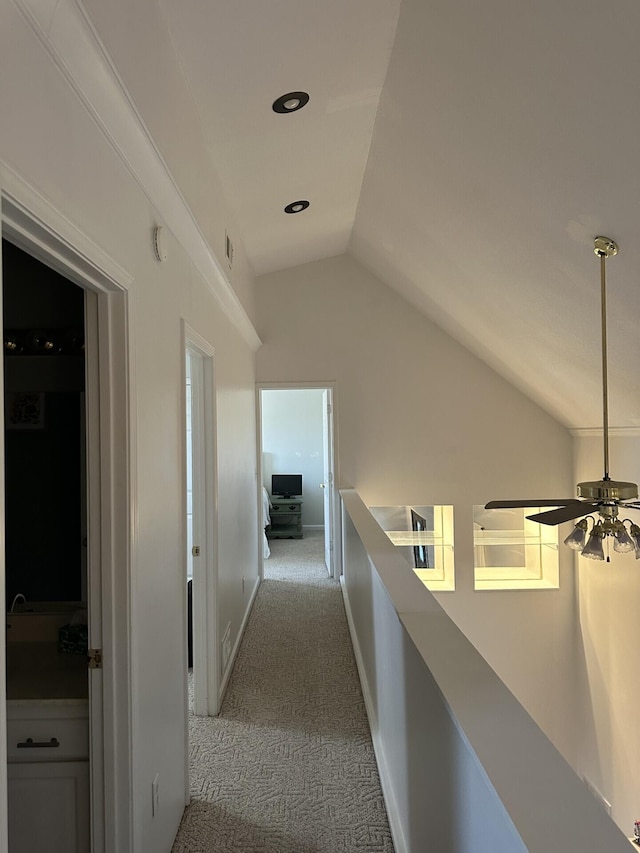 hallway featuring light carpet and vaulted ceiling