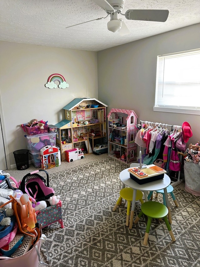 playroom with ceiling fan, carpet flooring, and a textured ceiling