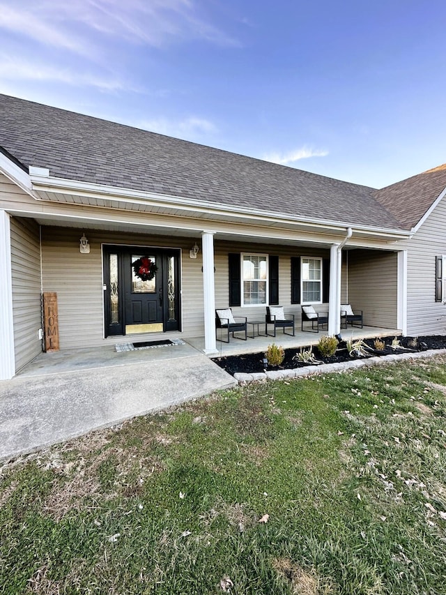 view of exterior entry with a porch and a yard