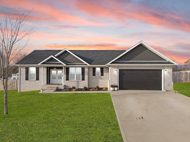 view of front of home featuring a garage, brick siding, fence, driveway, and a front yard