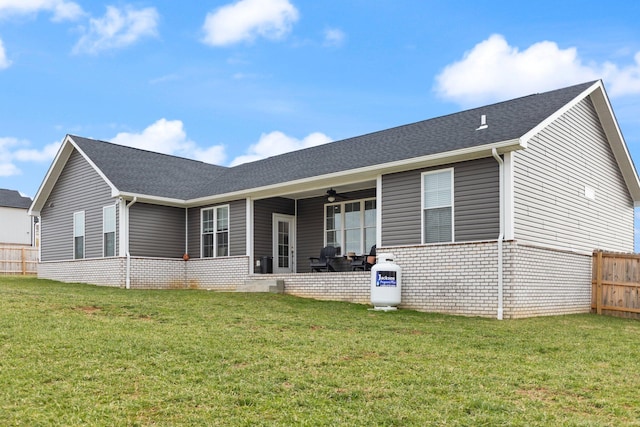 back of property with brick siding, ceiling fan, fence, and a lawn