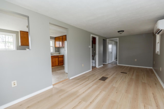 spare room featuring a wall mounted AC and light hardwood / wood-style floors