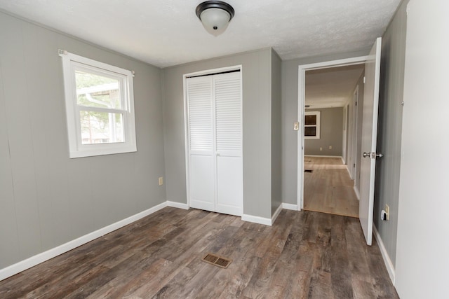 unfurnished bedroom featuring dark hardwood / wood-style flooring, a closet, and a textured ceiling