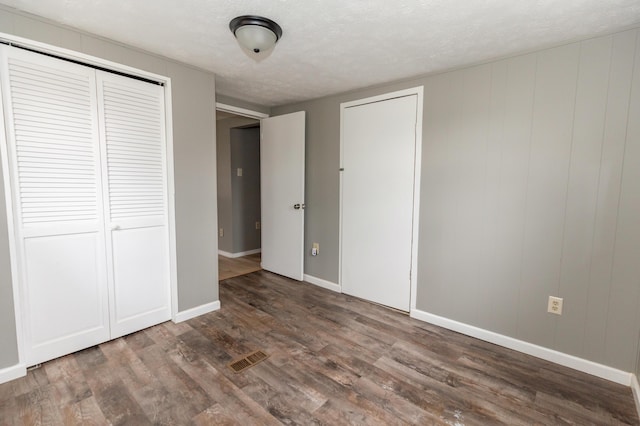 unfurnished bedroom with dark hardwood / wood-style flooring and a textured ceiling