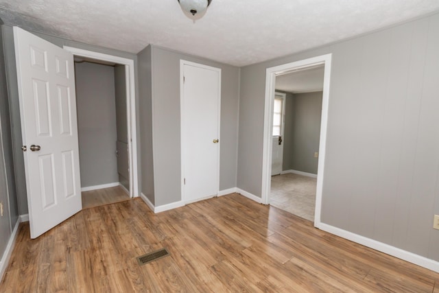 unfurnished bedroom featuring a textured ceiling, light wood-type flooring, and a closet