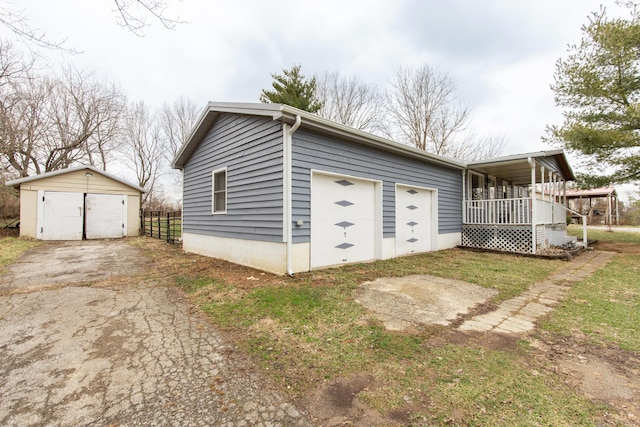 view of property exterior featuring a porch, a garage, and an outbuilding