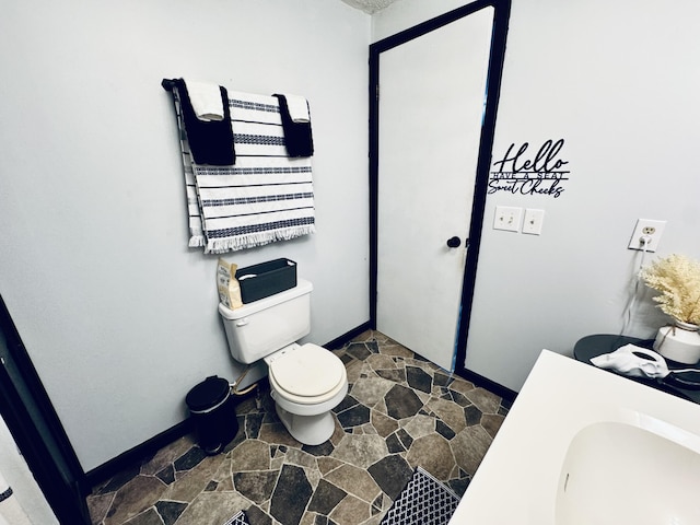 6002 Edmonton Rd, Columbia, KY 42728 - bathroom featuring stone finish floors, toilet, a sink, and baseboards
