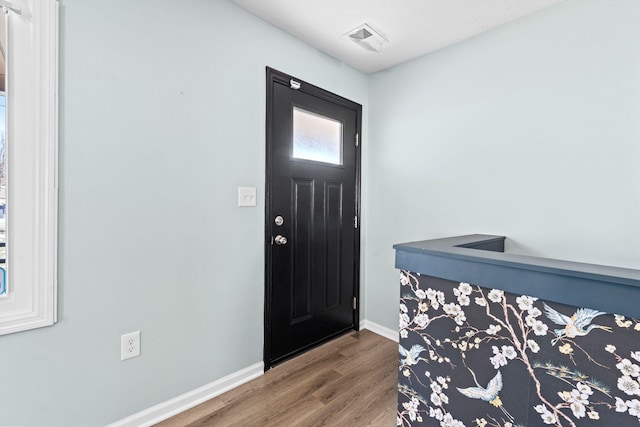 entryway with baseboards, visible vents, and wood finished floors