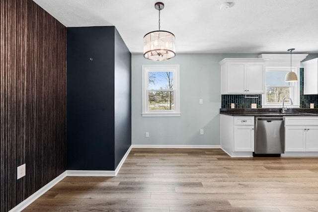 kitchen featuring dark countertops, white cabinets, dishwasher, and a sink