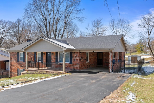 single story home with aphalt driveway, a storage shed, brick siding, an outdoor structure, and roof with shingles