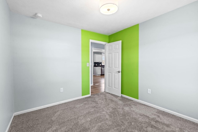 unfurnished room with carpet and baseboards