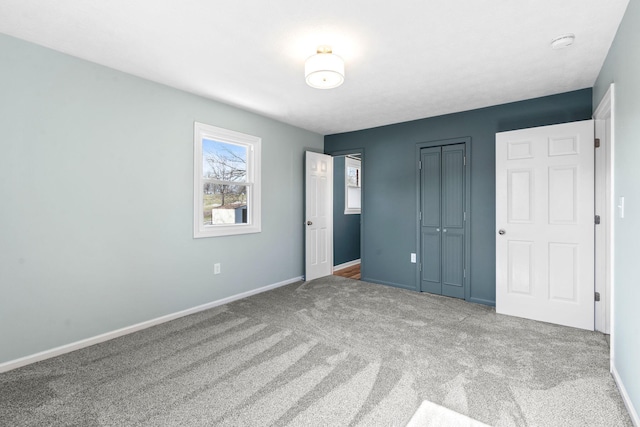 unfurnished bedroom with carpet floors, a closet, and baseboards