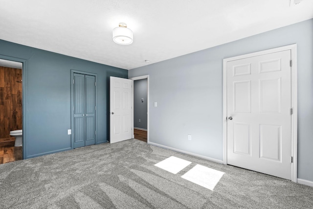 unfurnished bedroom featuring carpet, a closet, baseboards, and ensuite bathroom